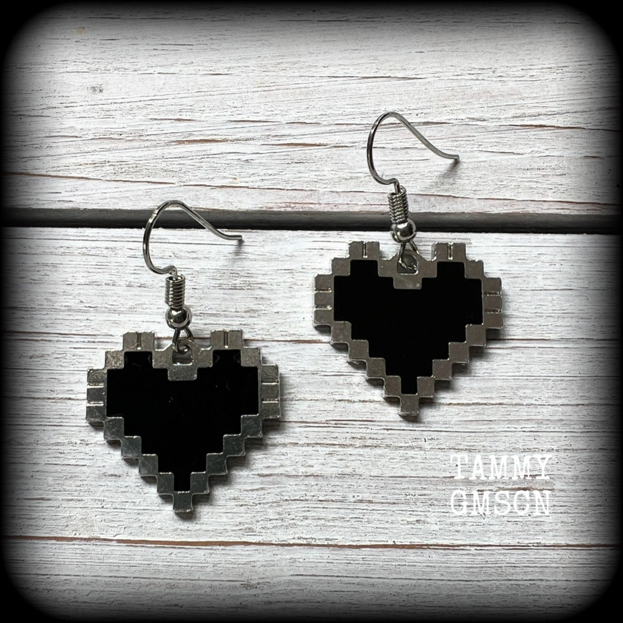 This pair of super cute earrings features black enamel and antique silver pixel hearts, measuring just under 4cms from tip to tip, and weighing only a few grams each.

This pair has been made with stainless steel french hooks, to be worn in pierced ears.