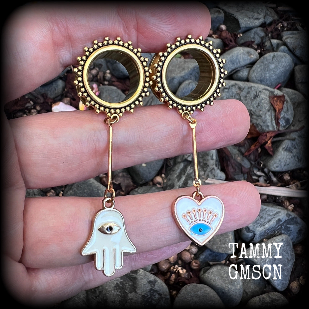 These tunnel earrings feature gold enamel hamsa hand and evil eye charms, weighing approx 9 grams each and measuring just over 6cms.
This pair have been made with 5/8" (16mm) gauge ornate titanium coated surgical steel screw fit tunnels.
