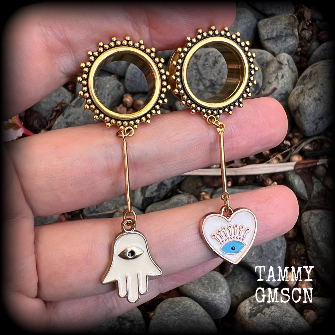 These tunnel earrings feature gold enamel hamsa hand and evil eye charms, weighing approx 9 grams each and measuring just over 6cms.
This pair have been made with 5/8" (16mm) gauge ornate titanium coated surgical steel screw fit tunnels.