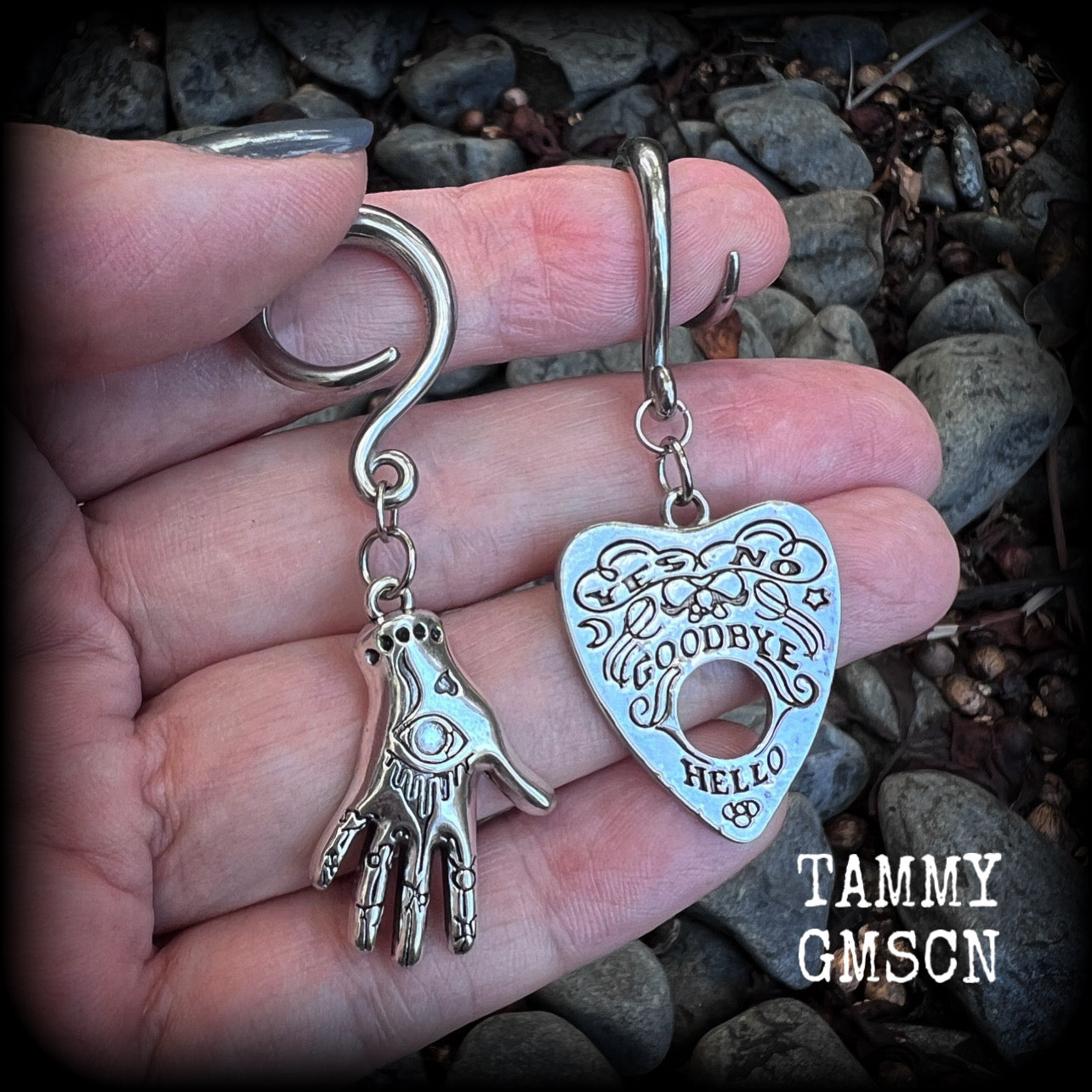 Featuring an antique silver Ouija planchette and esoteric hand charm, this pair of gorgeous earrings weigh approx 5 grams a piece, and measure 6cms from tip to tip.

This pair has been made on 6 gauge (4mm) surgical steel full curl hooks, suitable for stretched lobes.

