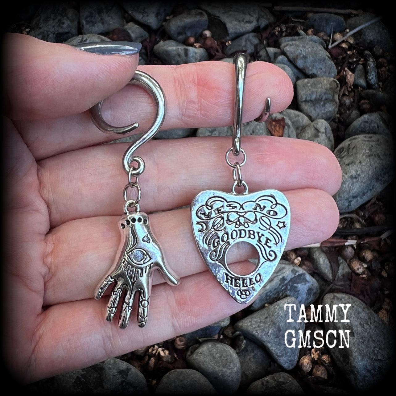 Featuring an antique silver Ouija planchette and esoteric hand charm, this pair of gorgeous earrings weigh approx 5 grams a piece, and measure 6cms from tip to tip.

This pair has been made on 6 gauge (4mm) surgical steel full curl hooks, suitable for stretched lobes.

