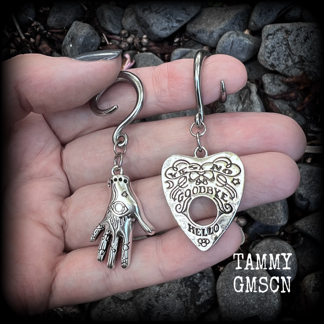 Featuring an antique silver Ouija planchette and esoteric hand charm, this pair of gorgeous earrings weigh approx 5 grams a piece, and measure 6cms from tip to tip.

This pair has been made on 6 gauge (4mm) surgical steel full curl hooks, suitable for stretched lobes.

