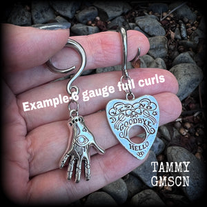 Featuring an antique silver Ouija planchette and esoteric hand charm, this pair of gorgeous earrings weigh approx 5 grams a piece, and measure 6cms from tip to tip.

This pair has been made on 6 gauge (4mm) surgical steel full curl hooks, suitable for stretched lobes.

