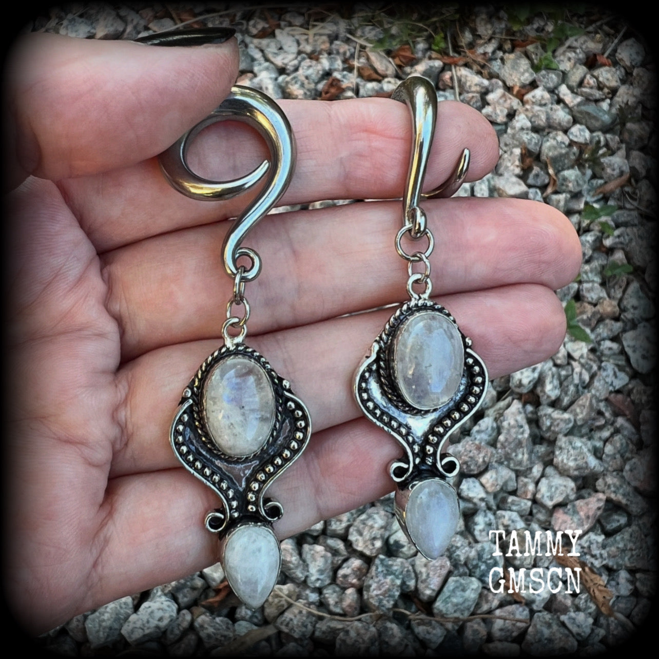 These gorgeous earrings feature polished Rainbow Moonstone gemstones in a beautiful boho antique silver setting, lovely and dangly at approx 8 cms from tip to tip, and not too heavy at 13 grams each.  This pair had been made on 2 gauge (6mm) surgical steel full curls, to be worn in stretched lobes.