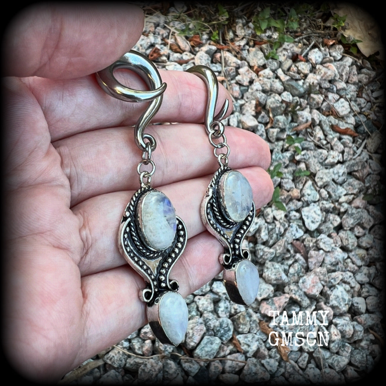 These gorgeous earrings feature polished Rainbow Moonstone gemstones in a beautiful boho antique silver setting, lovely and dangly at approx 8 cms from tip to tip, and not too heavy at 13 grams each.  This pair had been made on 2 gauge (6mm) surgical steel full curls, to be worn in stretched lobes.