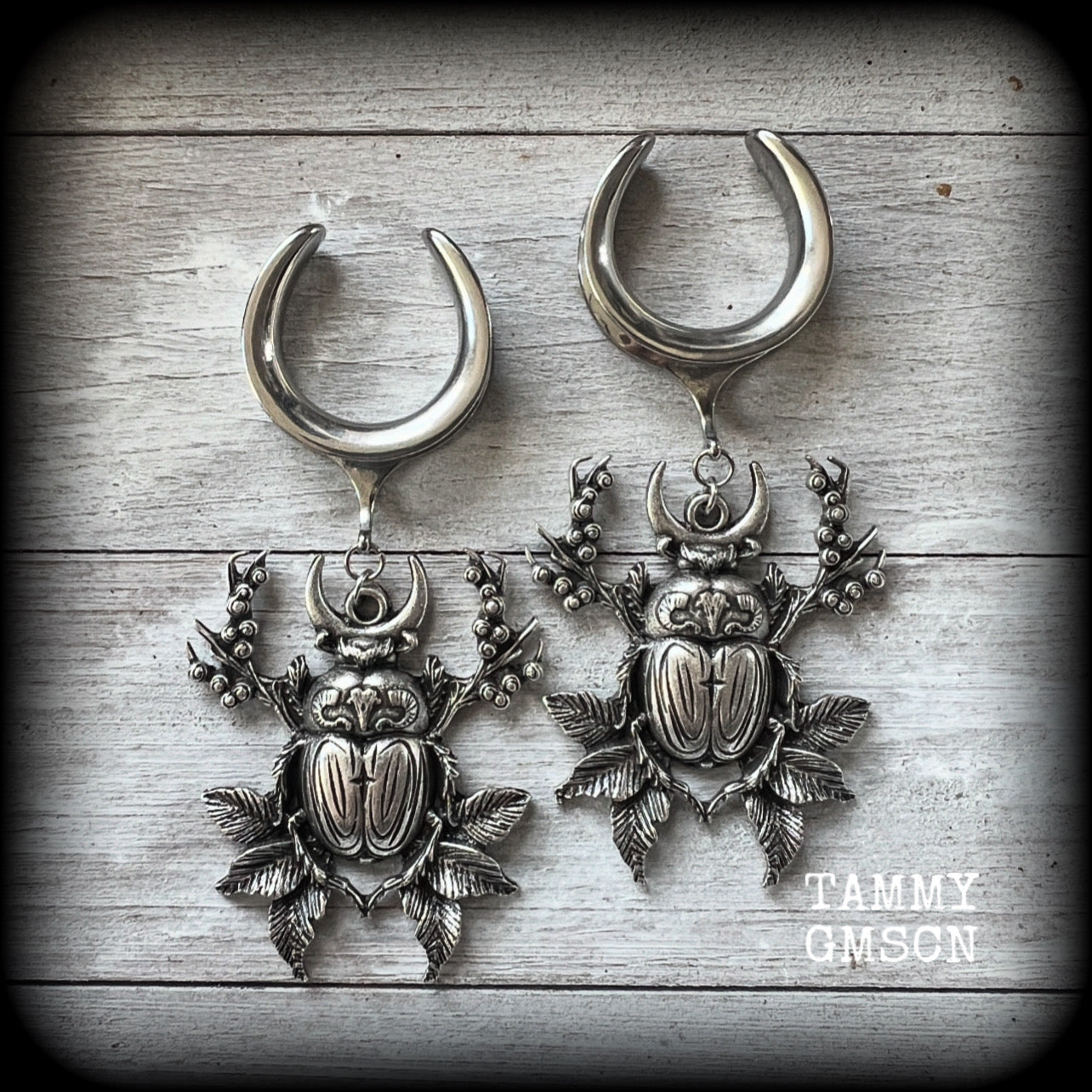 These gorgeous earrings feature large antique silver scarab beetles surrounded by berries and leaves with a crescent moon, measuring just on 9cms from tip to tip, and weighing 20 grams a piece.

This pair has been made on 1” gauge (25mm) gauge surgical steel cradles, to be worn in stretched lobes.