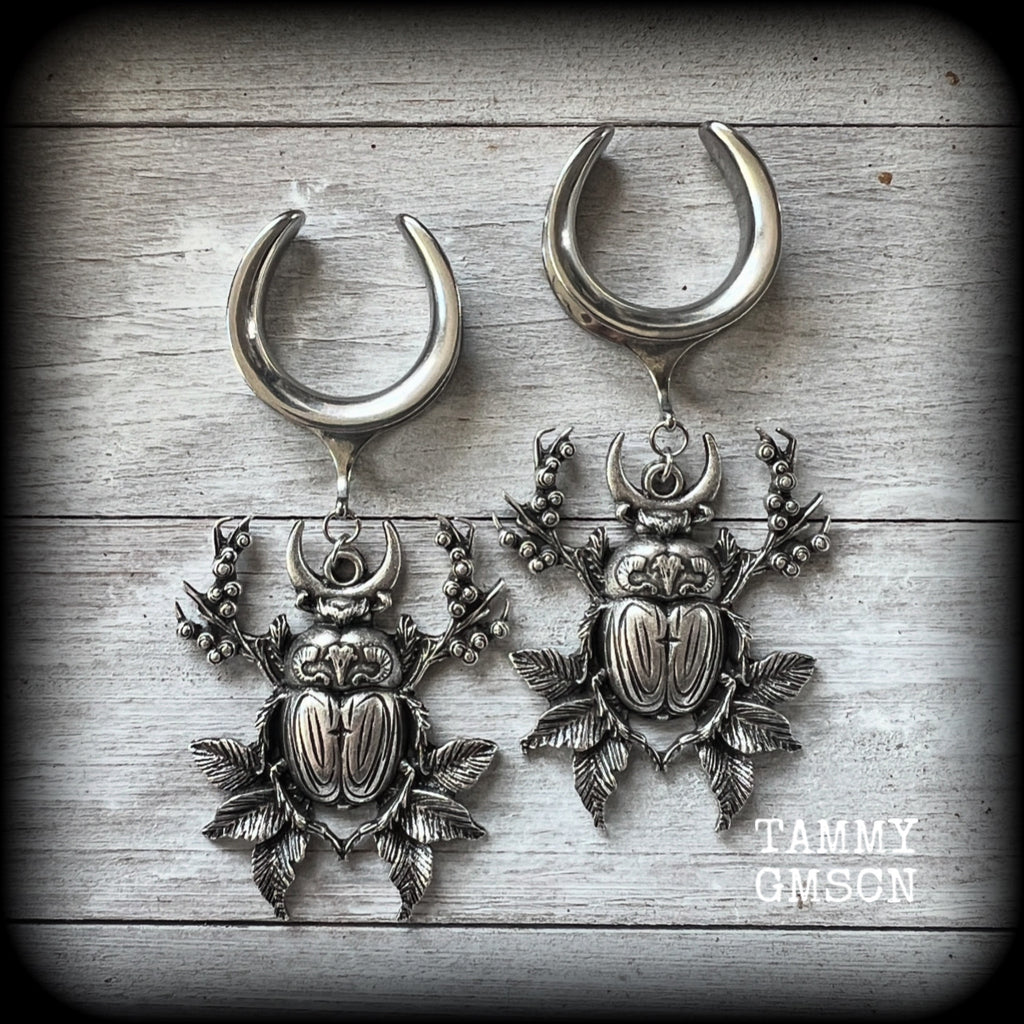 These gorgeous earrings feature large antique silver scarab beetles surrounded by berries and leaves with a crescent moon, measuring just on 9cms from tip to tip, and weighing 20 grams a piece.

This pair has been made on 1” gauge (25mm) gauge surgical steel cradles, to be worn in stretched lobes.