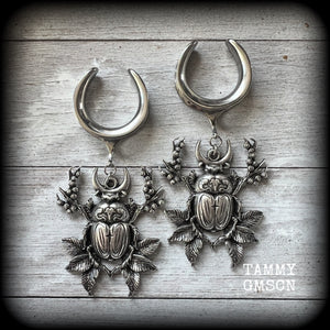 These gorgeous earrings feature large antique silver scarab beetles surrounded by berries and leaves with a crescent moon, measuring just on 9cms from tip to tip, and weighing 20 grams a piece.

This pair has been made on 1” gauge (25mm) gauge surgical steel cradles, to be worn in stretched lobes.