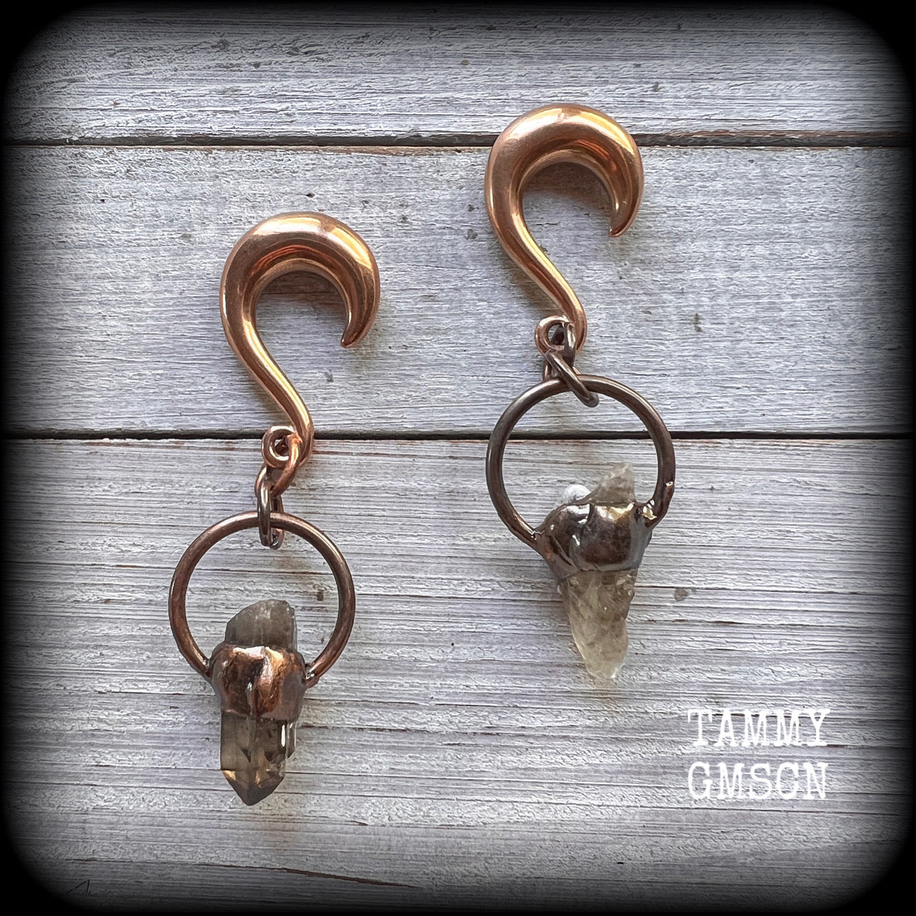 Featuring a pair of beautiful raw smokey quartz gemstones enclosed in rustic ornate copper plate hoop, this pair of gorgeous gauged earrings weighs approx 17 grams a piece, and measure approx 8cms from tip to tip.

This pair have been made on 0 gauge (8mm) rose gold titanium coated surgical steel half curl hooks, suitable for stretched lobes.