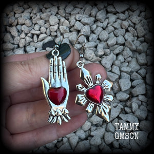 These beautiful red enamel and antique silver earrings feature a sacred heart with a sacred hand, are nice and lightweight at approx 5 grams a piece, measuring just on 6cms from tip to tip.

This pair has been made on stainless steel french hooks to be worn through pierced ears.
