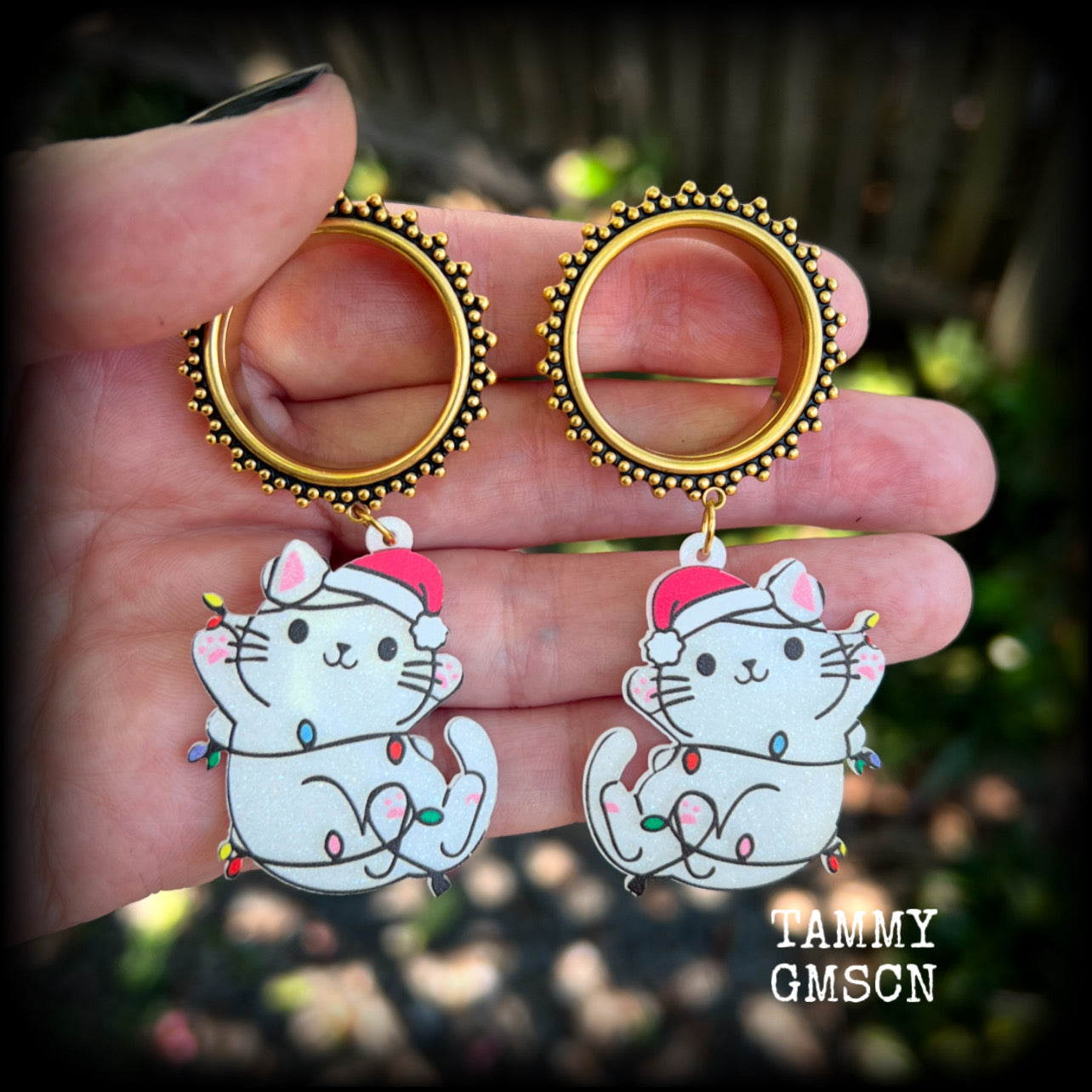 These festive tunnel earrings feature mischievous white cats in santa hats draped in Christmas lights, are nice and lightweight approx 12 grams each and measure just over 7cms from tip to tip.

This pair has been made on 1” gauge (25mm) gauge ornate surgical steel screw fit tunnels-for stretched lobes.