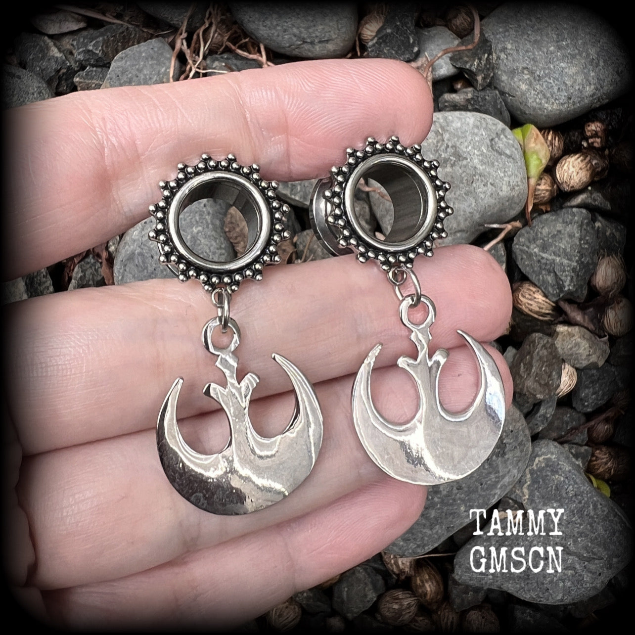 This pair of awesome Star Wars tunnel earrings features an antique silver Rebel Alliance symbol, measuring just on 5 cms from tip to tip, and weighing approx 7grams a piece. 

This pair has been made with gorgeous boho 1/2” gauge (12mm) ornate surgical steel screw fit tunnels, suitable for stretched lobes. 