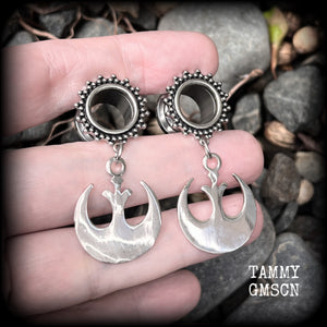 This pair of awesome Star Wars tunnel earrings features an antique silver Rebel Alliance symbol, measuring just on 5 cms from tip to tip, and weighing approx 7grams a piece. 

This pair has been made with gorgeous boho 1/2” gauge (12mm) ornate surgical steel screw fit tunnels, suitable for stretched lobes. 