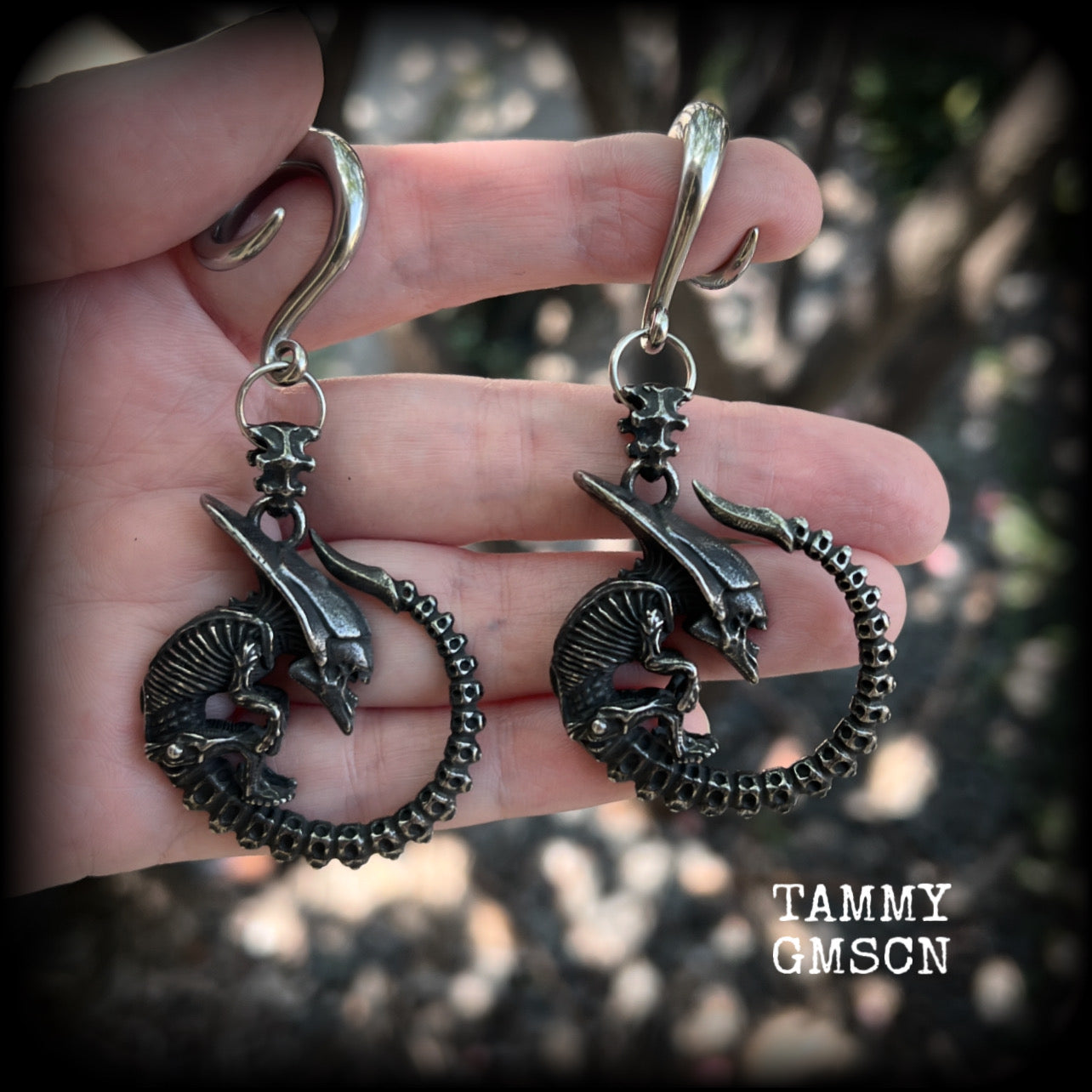 This pair of awesome ear hangers features a pair of gun metal grey antique silver Xenomorphs, weighing in at approx 28 grams a piece, and nice and dangly at 8cms from tip to tip. 

This pair has been made on 2 gauge (6mm) surgical steel full curl hooks, suitable for stretched lobes.
