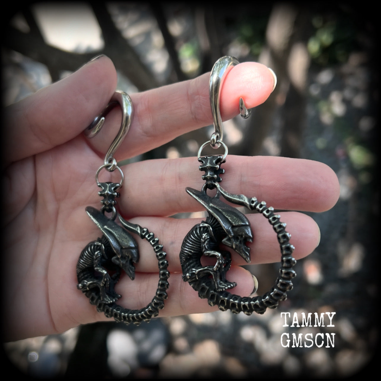 This pair of awesome ear hangers features a pair of gun metal grey antique silver Xenomorphs, weighing in at approx 28 grams a piece, and nice and dangly at 8cms from tip to tip. 

This pair has been made on 2 gauge (6mm) surgical steel full curl hooks, suitable for stretched lobes.
