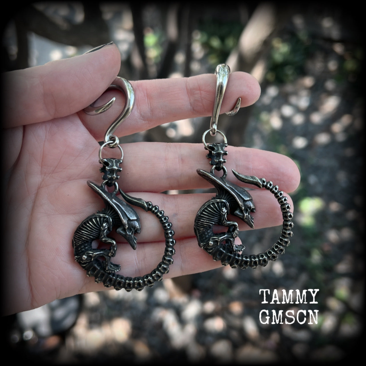 This pair of awesome ear hangers features a pair of gun metal grey antique silver Xenomorphs, weighing in at approx 28 grams a piece, and nice and dangly at 8cms from tip to tip. 

This pair has been made on 2 gauge (6mm) surgical steel full curl hooks, suitable for stretched lobes.

