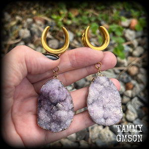 This is a pair of dusty purple druzy earrings featuring real druzy gems in an antique gold setting.
Measuring just 7.5 cms from tip to tip, and weighing approx 25 & 35 grams each.
This pair has been made on 3/4” gauge (19mm) surgical steel cradles.