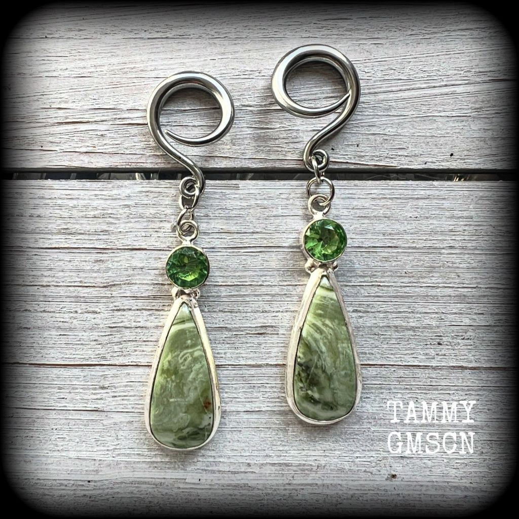 These beautiful Serpentine and green garnet earrings are made with gorgeous polished and faceted gemstones, lovely and dangly measuring just approx 7.5cms from tip to tip, and weighing approx 9 grams each. 

These earrings have been made on 6 gauge (4mm) surgical steel full curl hooks, to be worn in stretched lobes.
