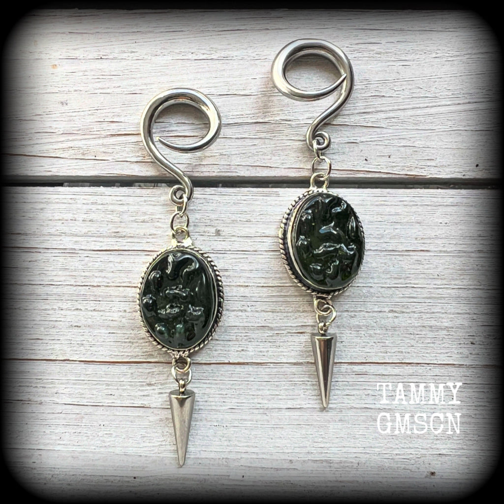 This pair of earrings features gorgeous forest green moldavite gemstones in a boho antique silver setting, weighing approx 10 grams a piece and measuring just on 8cms from tip to tip.

This pair have been made on 6 gauge (4mm) surgical steel full curl hooks, to be worn in stretched lobes.