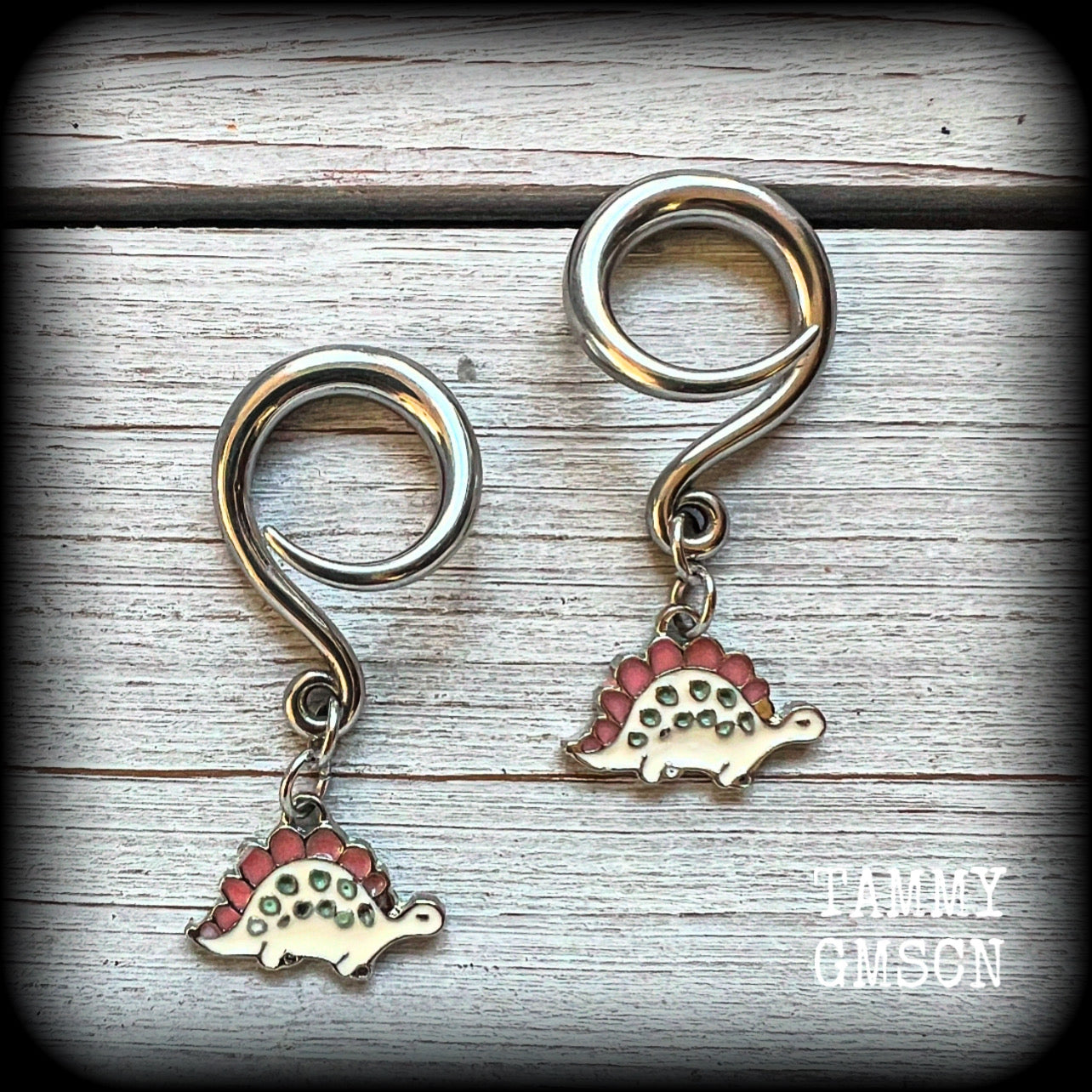 These adorable pink and white enamel stegosaurus gauged earrings are nice and light weight at approx 5 grams a piece, and nice and dangly at just under 5cms from tip to tip.

This pair has been made on 6 gauge (4mm) surgical steel full curl hooks, to be worn in stretched lobes.