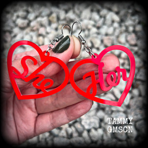 These earrings feature gorgeous bright red hearts showing the pronouns SHE/HER. 
These are nice and lightweight (at only a few grams each), and measure approx 6.5cms from tip to tip.

This pair have been made on stainless steel french hooks, for pierced ears.