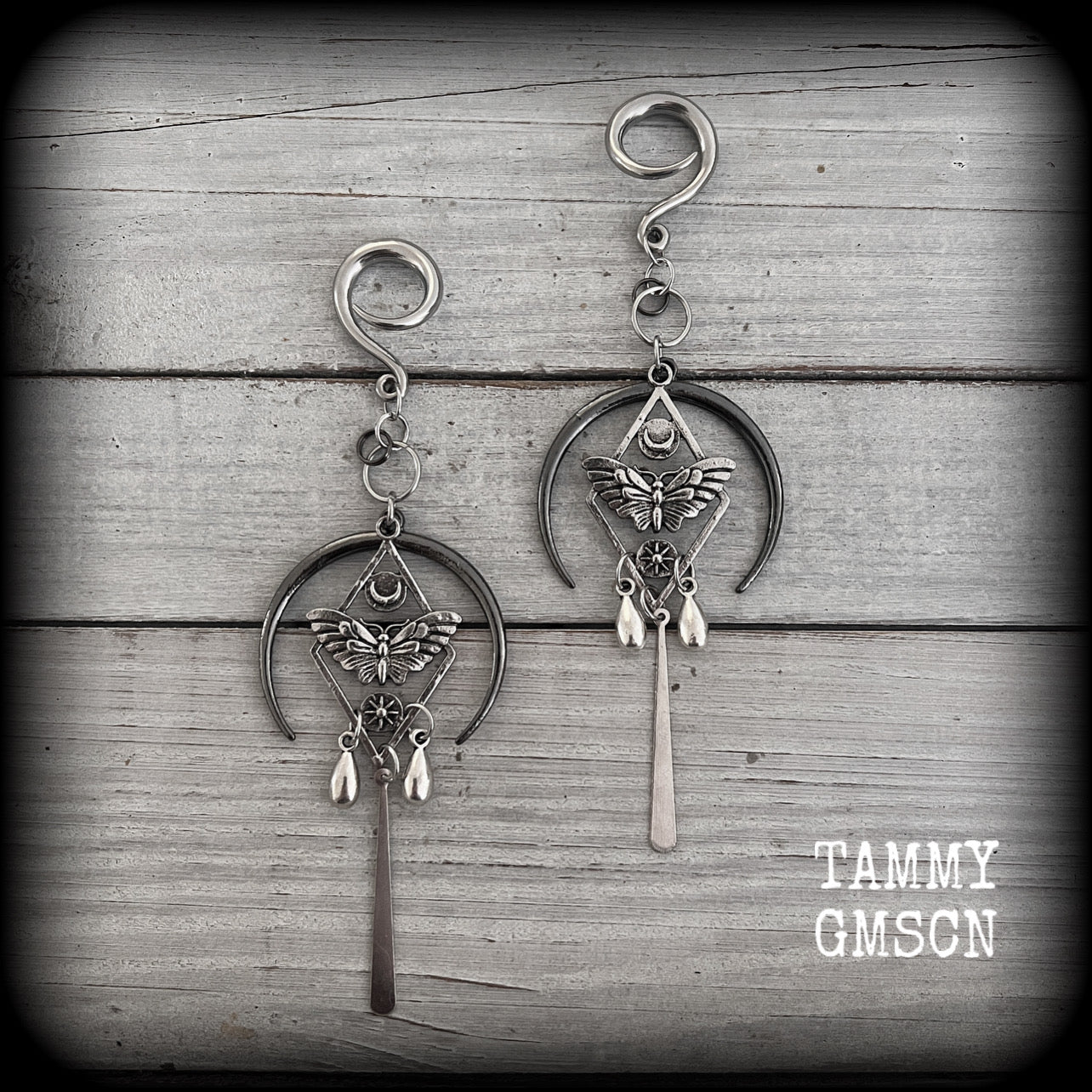 These gorgeous antique silver 'Moth and moon" gauged earrings feature an antique silver moth pendant sitting atop a black inverted crescent moon charm, dripping with antique silver teardrops.
Measuring just under 11cms, weighing approx 11 grams each.