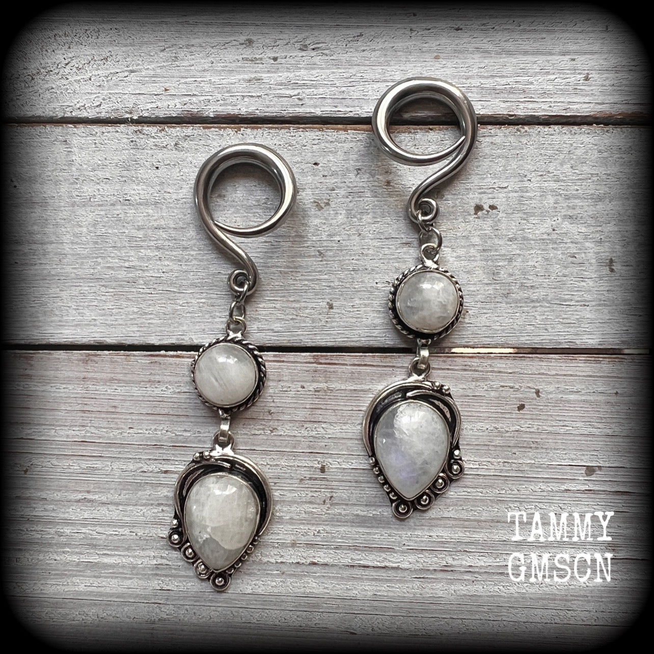 These gorgeous earrings feature polished Rainbow Moonstone gemstones in a beautiful boho antique silver setting, lovely and dangly at approx 8cms from tip to tip, and not too heavy at 9 grams each.
This pair had been made on 6 gauge (4mm) surgical steel full curl hooks, to be worn in stretched lobes.