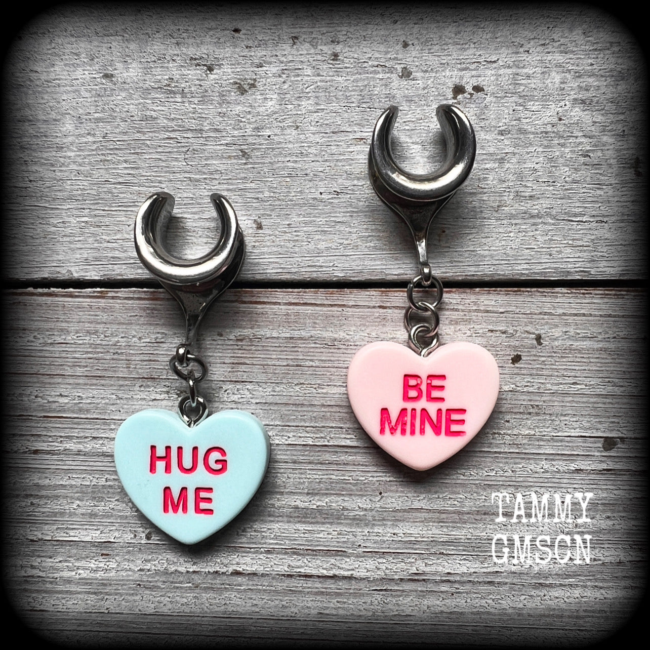 These adorable candy heart ear hangers feature mismatched Be mine and Hug me candy hearts, measuring just under 5cms from tip to tip, and weighing only a few grams each.
This pair has been made on 6 gauge (4mm) surgical steel full curl hooks, suitable for stretched lobes.