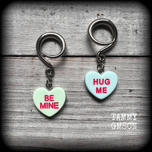 These adorable candy heart ear hangers feature mismatched Be mine and Hug me candy hearts, measuring just under 5cms from tip to tip, and weighing only a few grams each.
This pair has been made on 6 gauge (4mm) surgical steel full curl hooks, suitable for stretched lobes.