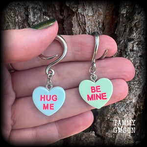 These adorable candy heart ear hangers feature mismatched Be mine and Hug me candy hearts, measuring just under 5cms from tip to tip, and weighing only a few grams each.
This pair has been made on 6 gauge (4mm) surgical steel full curl hooks.
