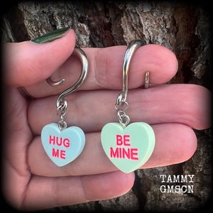 These adorable candy heart ear hangers feature mismatched Be mine and Hug me candy hearts, measuring just under 5cms from tip to tip, and weighing only a few grams each.
This pair has been made on 6 gauge (4mm) surgical steel full curl hooks.