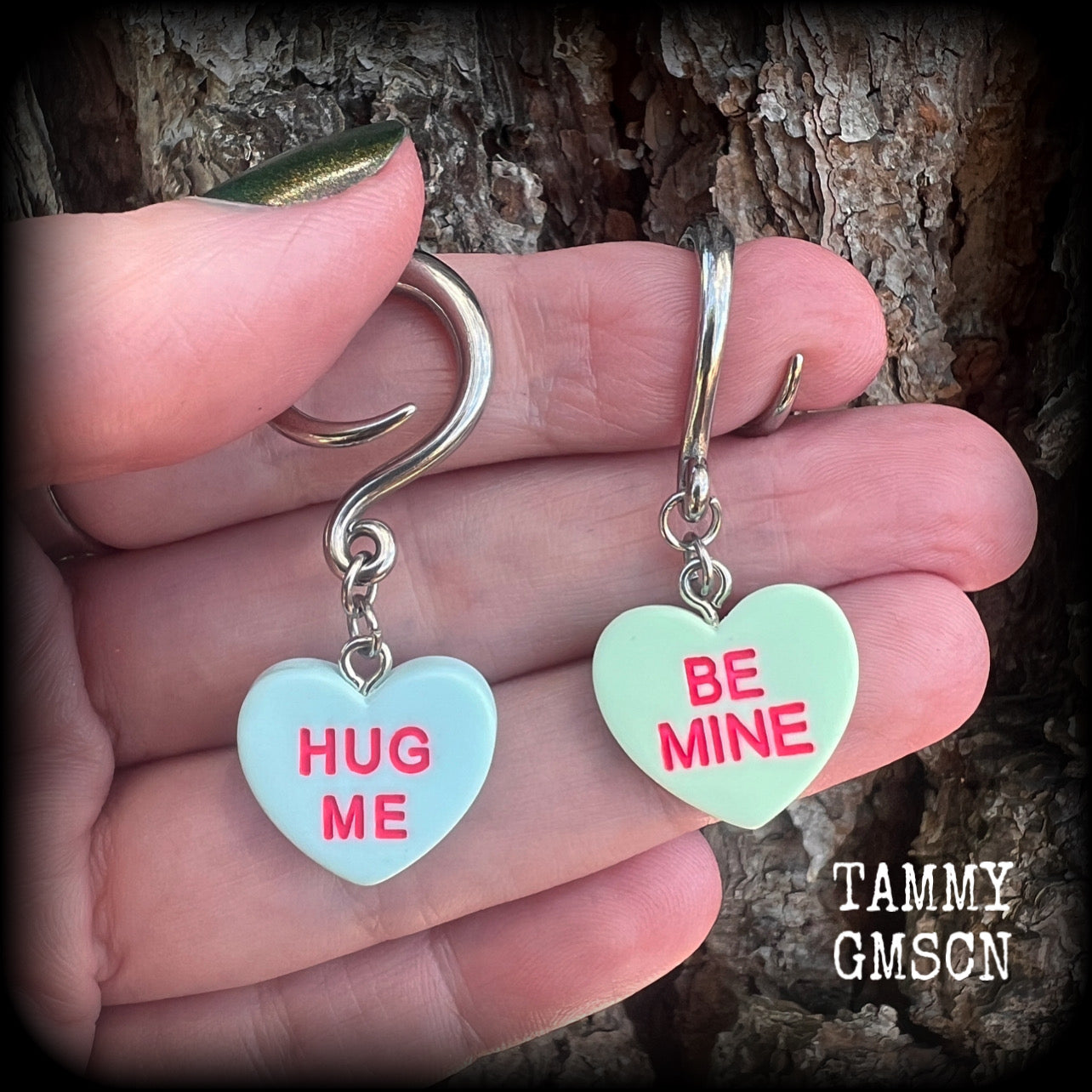 These adorable candy heart ear hangers feature mismatched Be mine and Hug me candy hearts, measuring just under 5cms from tip to tip, and weighing only a few grams each.
This pair has been made on 6 gauge (4mm) surgical steel full curl hooks.