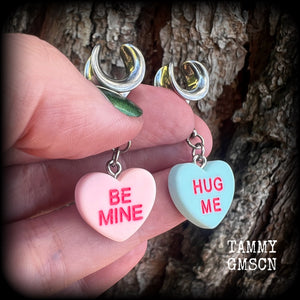 These adorable candy heart ear hangers feature mismatched Be mine and Hug me candy hearts, measuring just under 5cms from tip to tip, and weighing only a gram or two each.
This pair has been made on 00 gauge (10mm) surgical steel cradles.