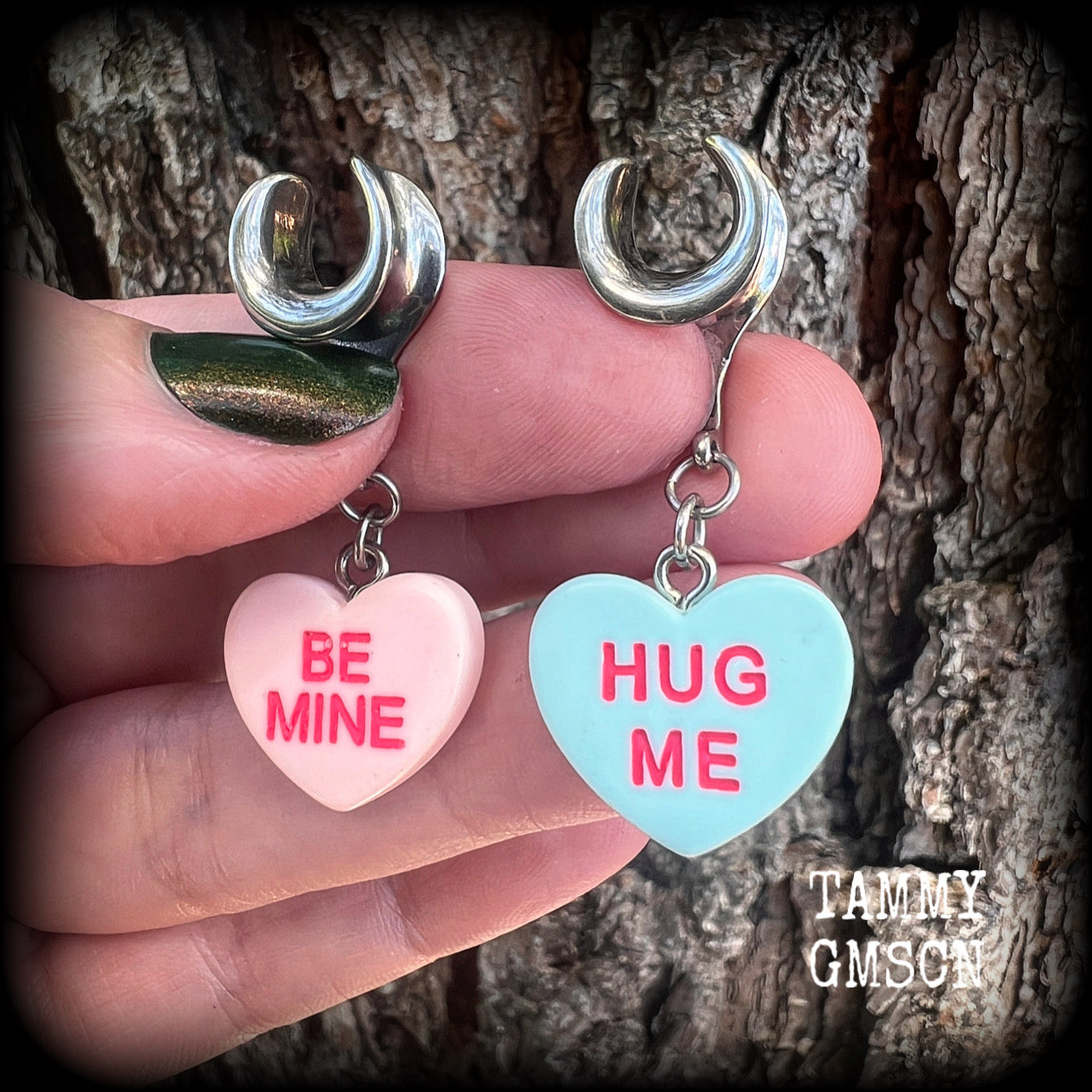 These adorable candy heart ear hangers feature mismatched Be mine and Hug me candy hearts, measuring just under 5cms from tip to tip, and weighing only a gram or two each.
This pair has been made on 00 gauge (10mm) surgical steel cradles.