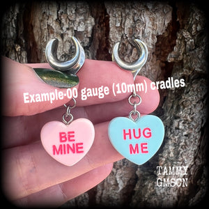 These adorable candy heart ear hangers feature mismatched Be mine and Hug me candy hearts, measuring just under 5cms from tip to tip, and weighing only a gram or two each.
This pair has been made on 00 gauge (10mm) surgical steel cradles.