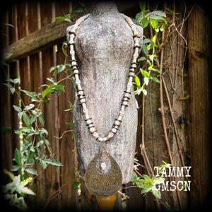 This unique necklace features a gorgeous antique bronze abstract snake pendant with a small bone white howlite stone skull dangling atop, on a strand of bone white stone and ornate antique bronze beads.
This necklace measures 44cms from tip to tip when laid flat and fastens with an antique bronze lobster clasp.