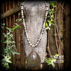 This unique necklace features a gorgeous antique bronze abstract snake pendant with a small bone white howlite stone skull dangling atop, on a strand of bone white stone and ornate antique bronze beads.
This necklace measures 44cms from tip to tip when laid flat and fastens with an antique bronze lobster clasp.