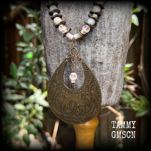 This unique necklace features a gorgeous antique bronze abstract snake pendant with a small bone white howlite stone skull dangling atop, on a strand of bone white stone and ornate antique bronze beads.
This necklace measures 44cms from tip to tip when laid flat and fastens with an antique bronze lobster clasp.