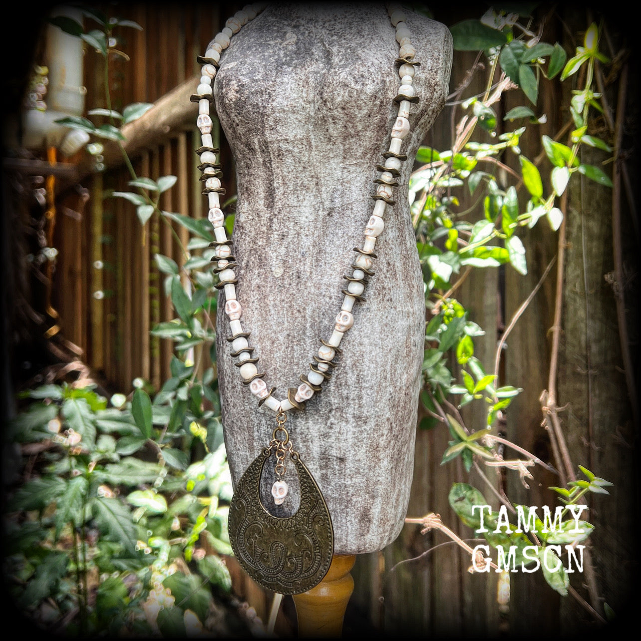 This unique necklace features a gorgeous antique bronze abstract snake pendant with a small bone white howlite stone skull dangling atop, on a strand of bone white stone and ornate antique bronze beads.
This necklace measures 44cms from tip to tip when laid flat and fastens with an antique bronze lobster clasp.