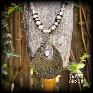 This unique necklace features a gorgeous antique bronze abstract snake pendant with a small bone white howlite stone skull dangling atop, on a strand of bone white stone and ornate antique bronze beads.
This necklace measures 44cms from tip to tip when laid flat and fastens with an antique bronze lobster clasp.