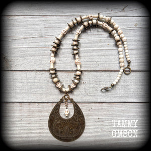 This unique necklace features a gorgeous antique bronze abstract snake pendant with a small bone white howlite stone skull dangling atop, on a strand of bone white stone and ornate antique bronze beads.
This necklace measures 44cms from tip to tip when laid flat and fastens with an antique bronze lobster clasp.