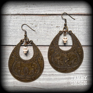 Inspired by Voodoo Sky-father Damballah, these earrings feature bone white skulls hanging from gorgeous antique bronze tear drop discs etched with a beautiful abstract serpent pattern.
Measuring 8cms from tip to tip, these unique earrings weigh 12 grams each, and have been made on antique bronze french hooks, suitable for pierced ears.