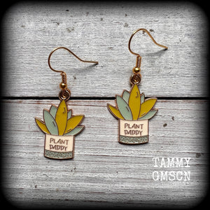 These quirky earrings feature an antique gold and enamel potted ‘PLANT DADDY’ plant, measuring just on 5cms from top to bottom, and weighing only a few grams each.

This pair has been made on antique gold french hooks, suitable for pierced ears.

