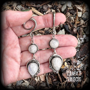 These gorgeous earrings feature polished Rainbow Moonstone gemstones in a beautiful boho antique silver setting, lovely and dangly at approx 8cms from tip to tip, and not too heavy at 9 grams each.
This pair had been made on 6 gauge (4mm) surgical steel full curl hooks, to be worn in stretched lobes.