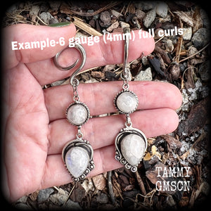These gorgeous earrings feature polished Rainbow Moonstone gemstones in a beautiful boho antique silver setting, lovely and dangly at approx 8cms from tip to tip, and not too heavy at 9 grams each.
This pair had been made on 6 gauge (4mm) surgical steel full curl hooks, to be worn in stretched lobes.