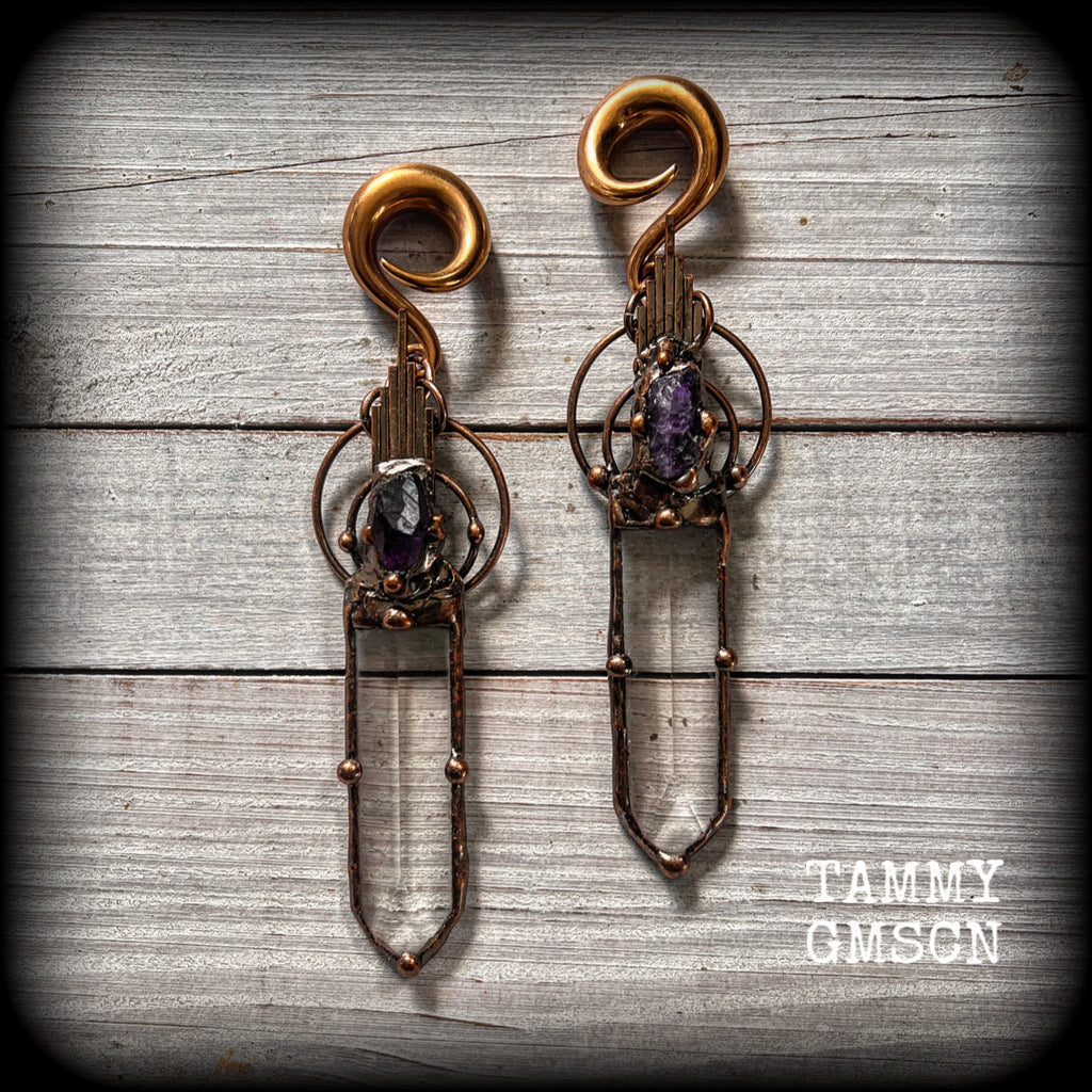 These beautiful oversized gauged earrings feature big clear quartz daggers with raw amethyst gemstones in a unique copper setting. These gorgeous earrings are nice and long, measuring 13cms from tip to tip, and weighing approx 47 grams each.
This pair has been made on 0 gauge (8mm) rose gold tone surgical steel full curl hooks, suitable for stretched lobes.