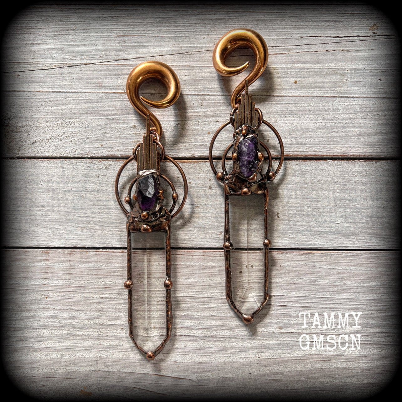 These beautiful oversized gauged earrings feature big clear quartz daggers with raw amethyst gemstones in a unique copper setting. These gorgeous earrings are nice and long, measuring 13cms from tip to tip, and weighing approx 47 grams each.
This pair has been made on 0 gauge (8mm) rose gold tone surgical steel full curl hooks, suitable for stretched lobes.