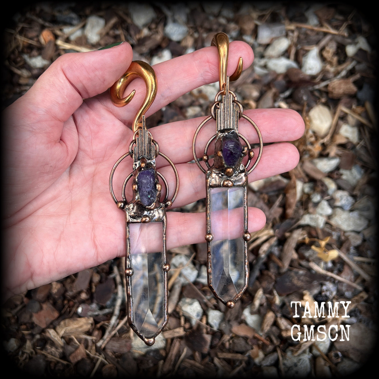 These beautiful oversized gauged earrings feature big clear quartz daggers with raw amethyst gemstones in a unique copper setting. These gorgeous earrings are nice and long, measuring 13cms from tip to tip, and weighing approx 47 grams each.
This pair has been made on 0 gauge (8mm) rose gold tone surgical steel full curl hooks, suitable for stretched lobes.