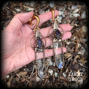 These beautiful oversized gauged earrings feature big clear quartz daggers with raw amethyst gemstones in a unique copper setting. These gorgeous earrings are nice and long, measuring 13cms from tip to tip, and weighing approx 47 grams each.
This pair has been made on 0 gauge (8mm) rose gold tone surgical steel full curl hooks, suitable for stretched lobes.