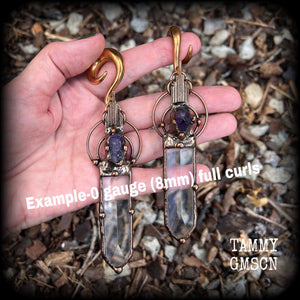 These beautiful oversized gauged earrings feature big clear quartz daggers with raw amethyst gemstones in a unique copper setting. These gorgeous earrings are nice and long, measuring 13cms from tip to tip, and weighing approx 47 grams each.
This pair has been made on 0 gauge (8mm) rose gold tone surgical steel full curl hooks, suitable for stretched lobes.